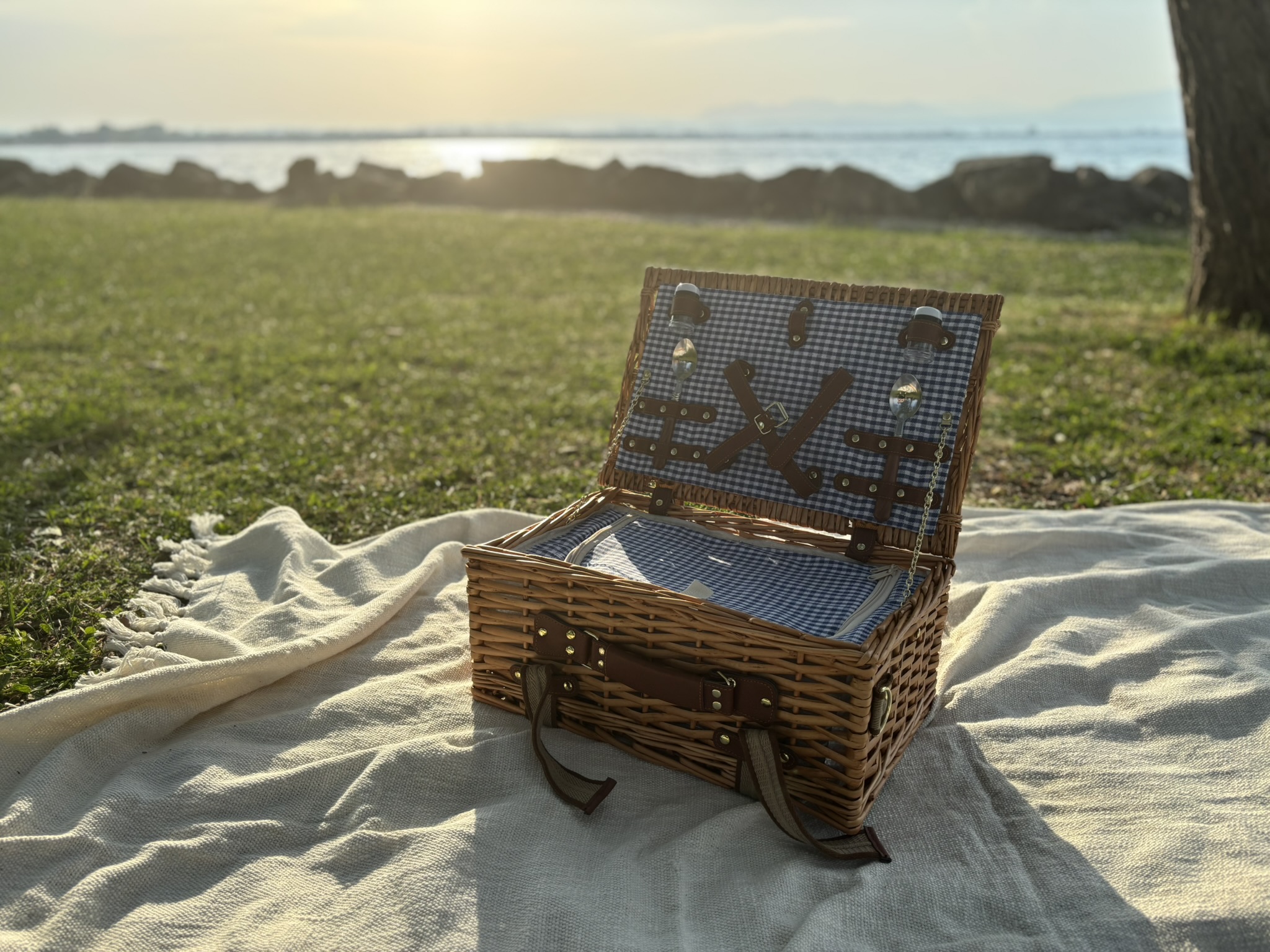 Cestino picnic in vimini chiuso sul telo di lino, Lago di Garda all'ora dorata